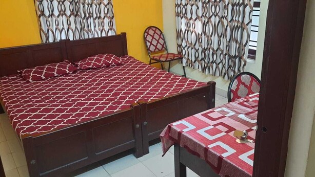 A bedroom with a bed, a chair, and a table.