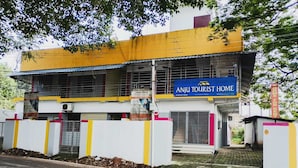A two-story building with a sign for 'Anju Tourist Home' and a sign indicating rooms for rent.