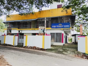 Un edificio de dos pisos con un letrero que dice 'Anju Tourist Home' y un letrero que indica habitaciones disponibles.
