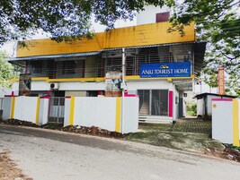 Un edificio de dos pisos con un letrero que dice 'Anju Tourist Home' y un letrero que indica habitaciones disponibles.