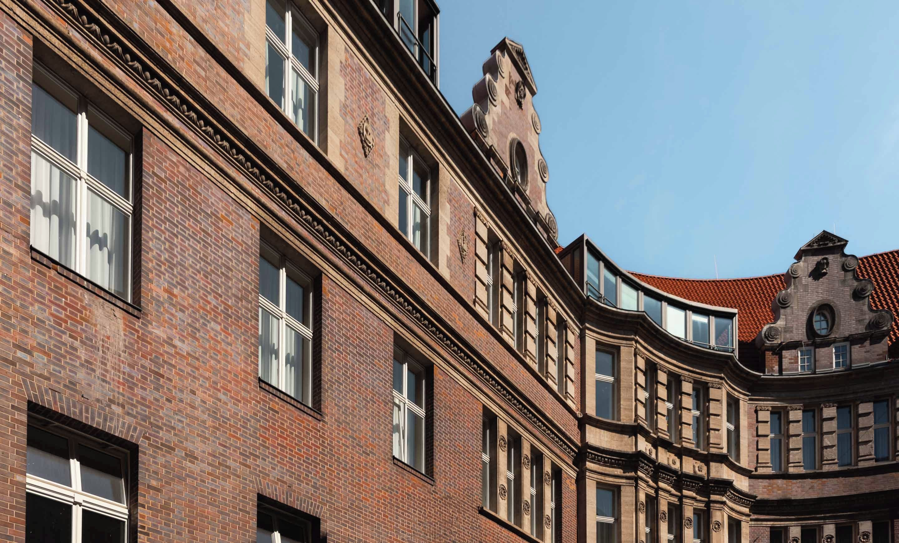 Un edificio a più piani con facciata in mattoni, ampie finestre e un design caratteristico all'angolo.
