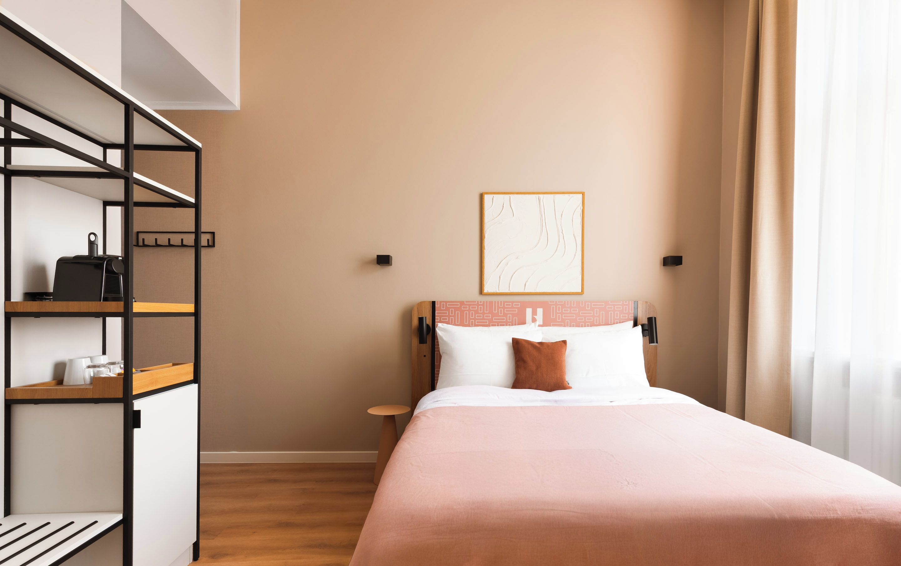 Ein Hotelzimmer mit einem Bett, einem Nachttisch, einer Regaleinheit und einem Wandbild.