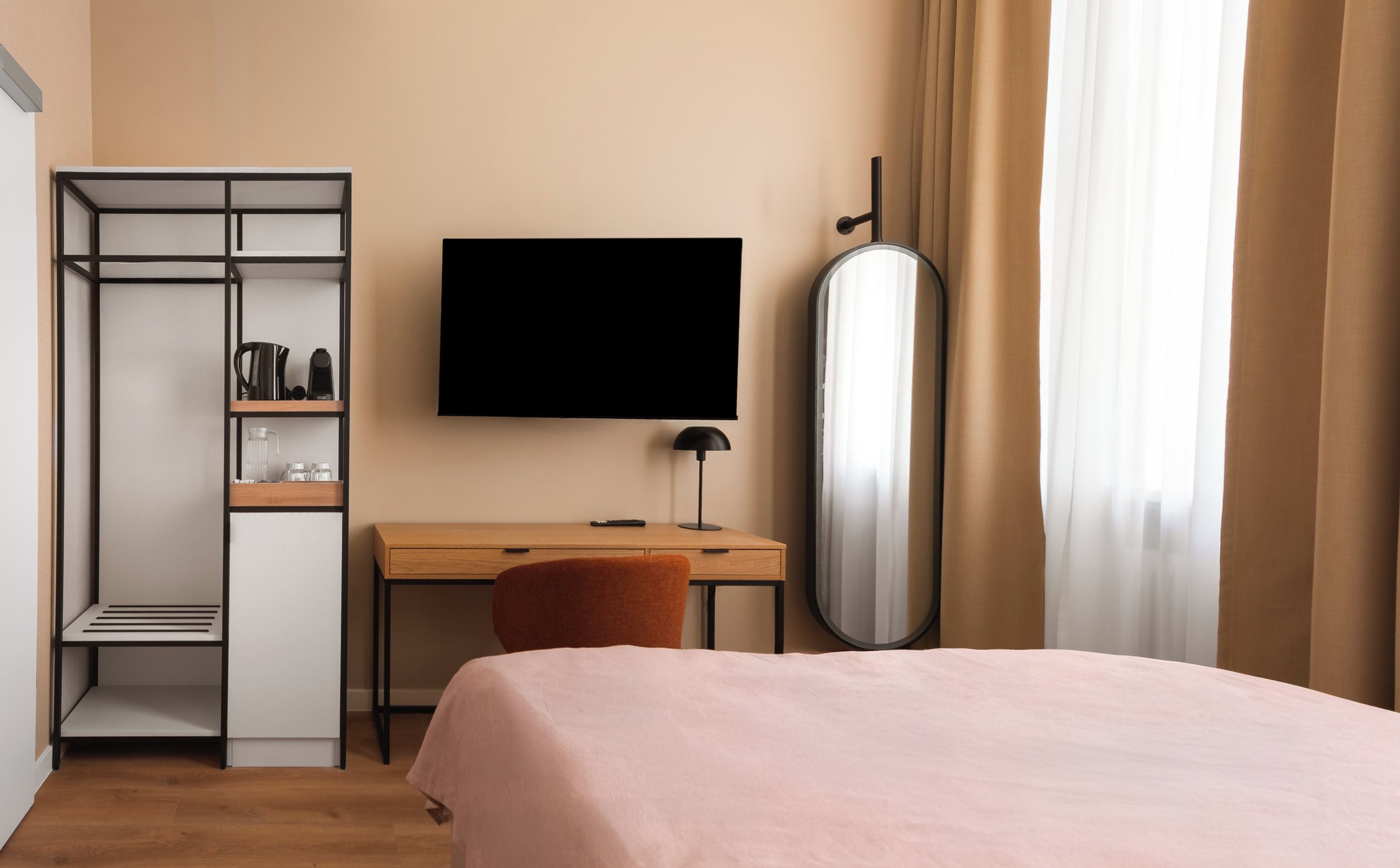 Habitació d'hotel amb llit, escriptori, televisió, armari i mirall.