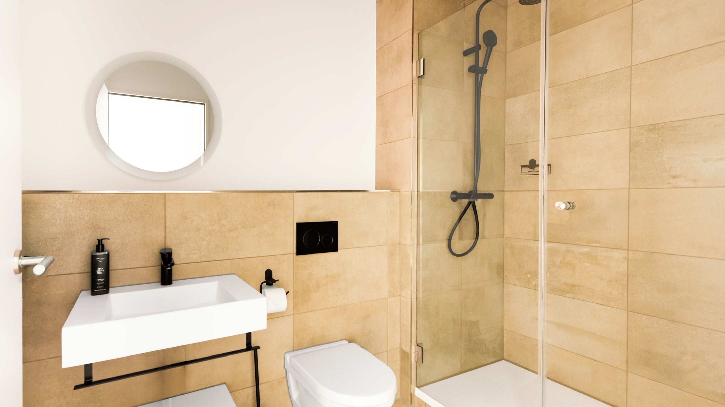 Une salle de bain avec un lavabo blanc, des toilettes et une douche séparée par une paroi de verre.