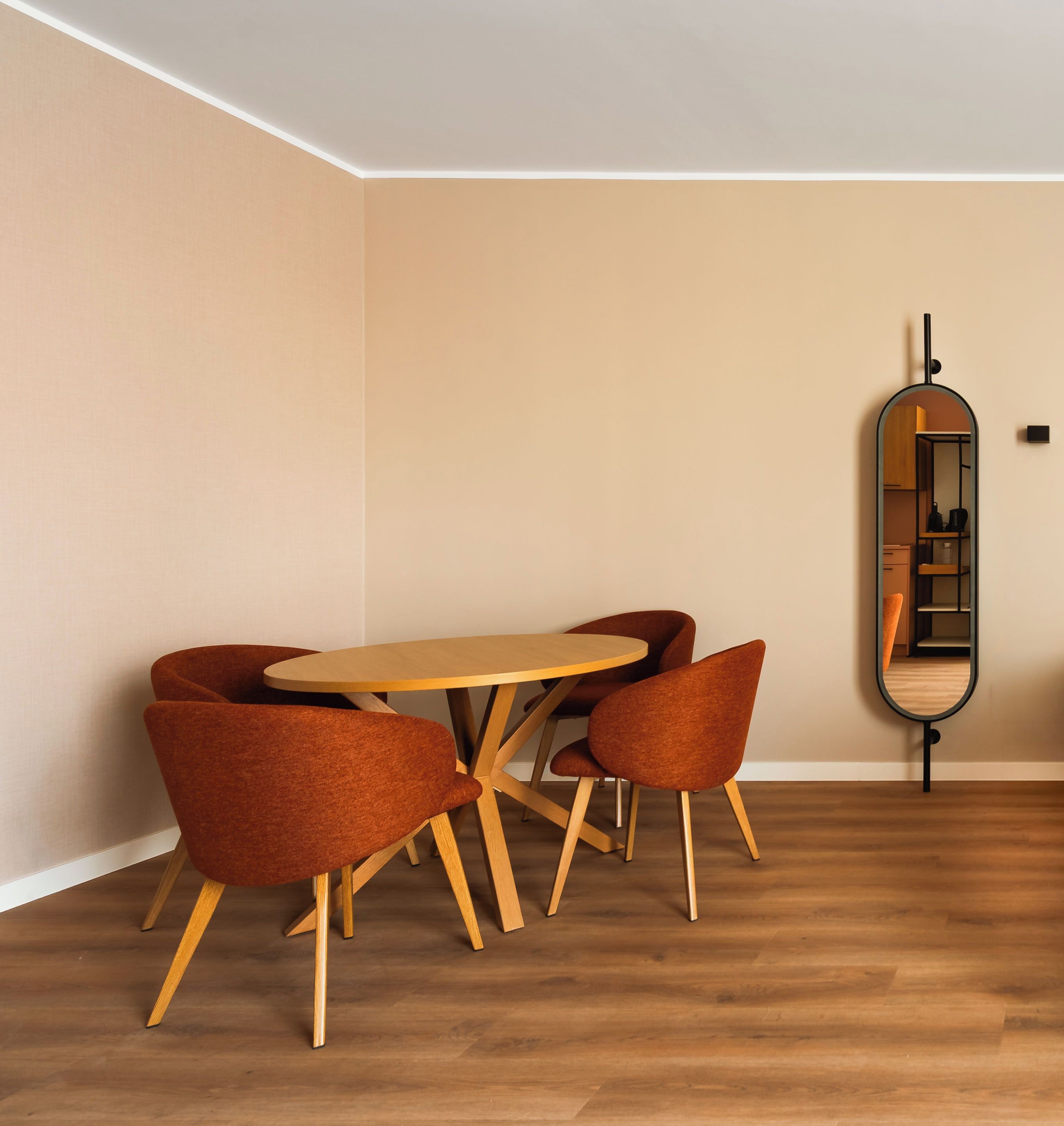 Ein Essbereich mit einem runden Holztisch und vier passenden Stühlen, einem Spiegel an der Wand und einem Holzboden.