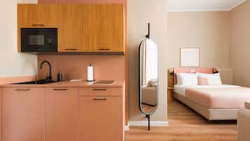 Ein modernes Hotelzimmer mit einer Küchenzeile, einem Bett, einem Nachttisch und einem Spiegel.