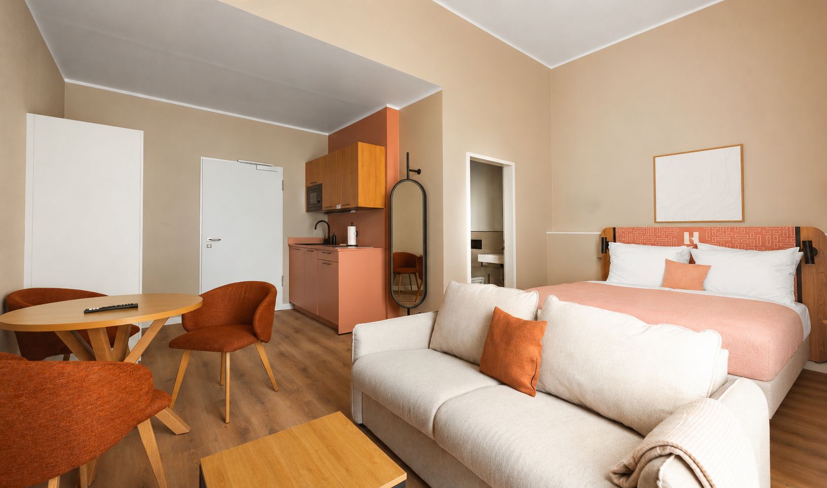 Ein Hotelzimmer mit Bett, einer Couch, einem Esstisch und einer Küchenzeile.