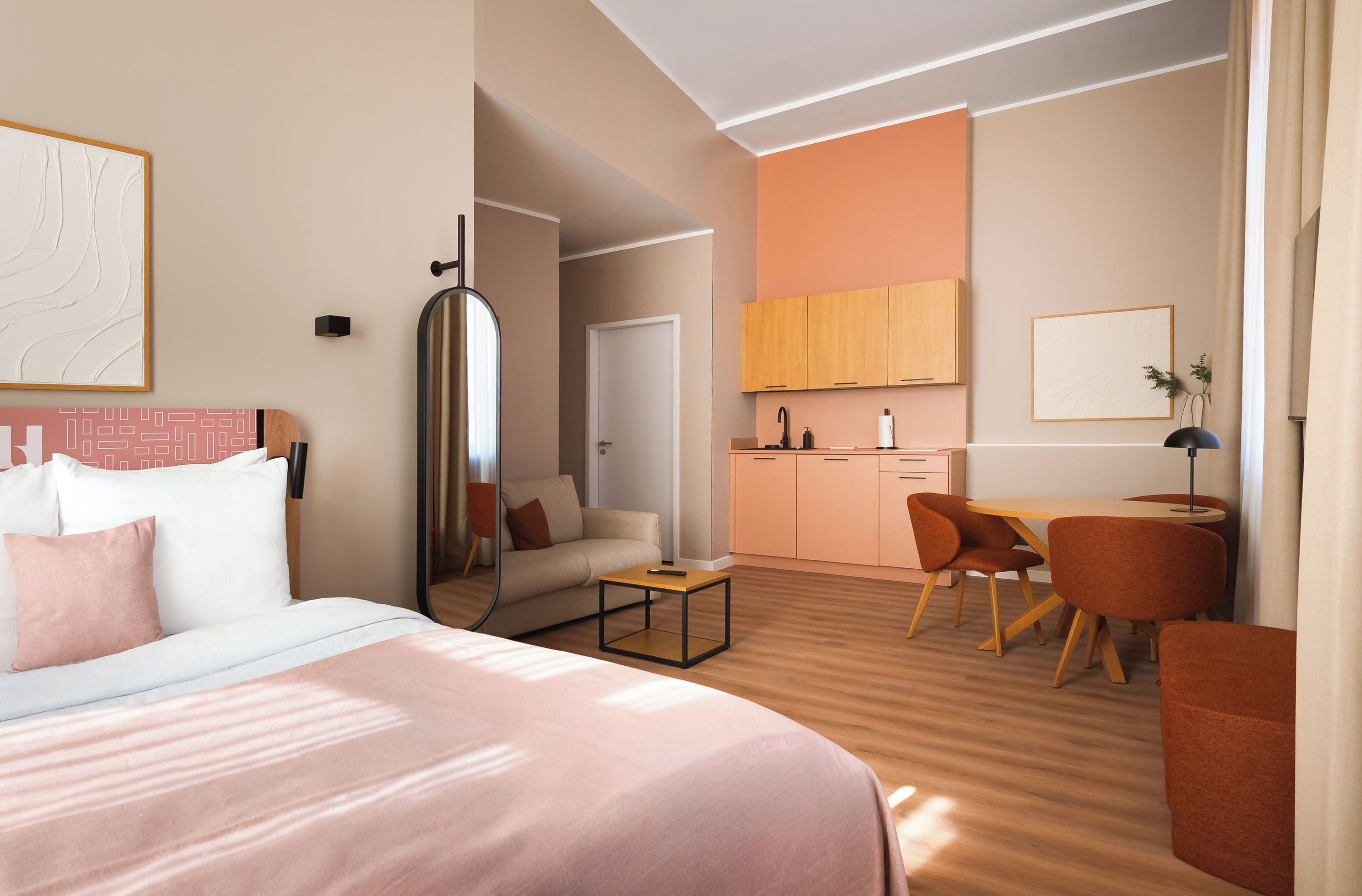 Una habitación de hotel moderna con cama, sofá, escritorio y una zona de cocina.