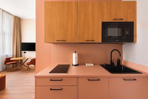 Una cocina moderna con armarios de madera, un microondas negro, un lavamanos y un comedor con mesa y sillas.
