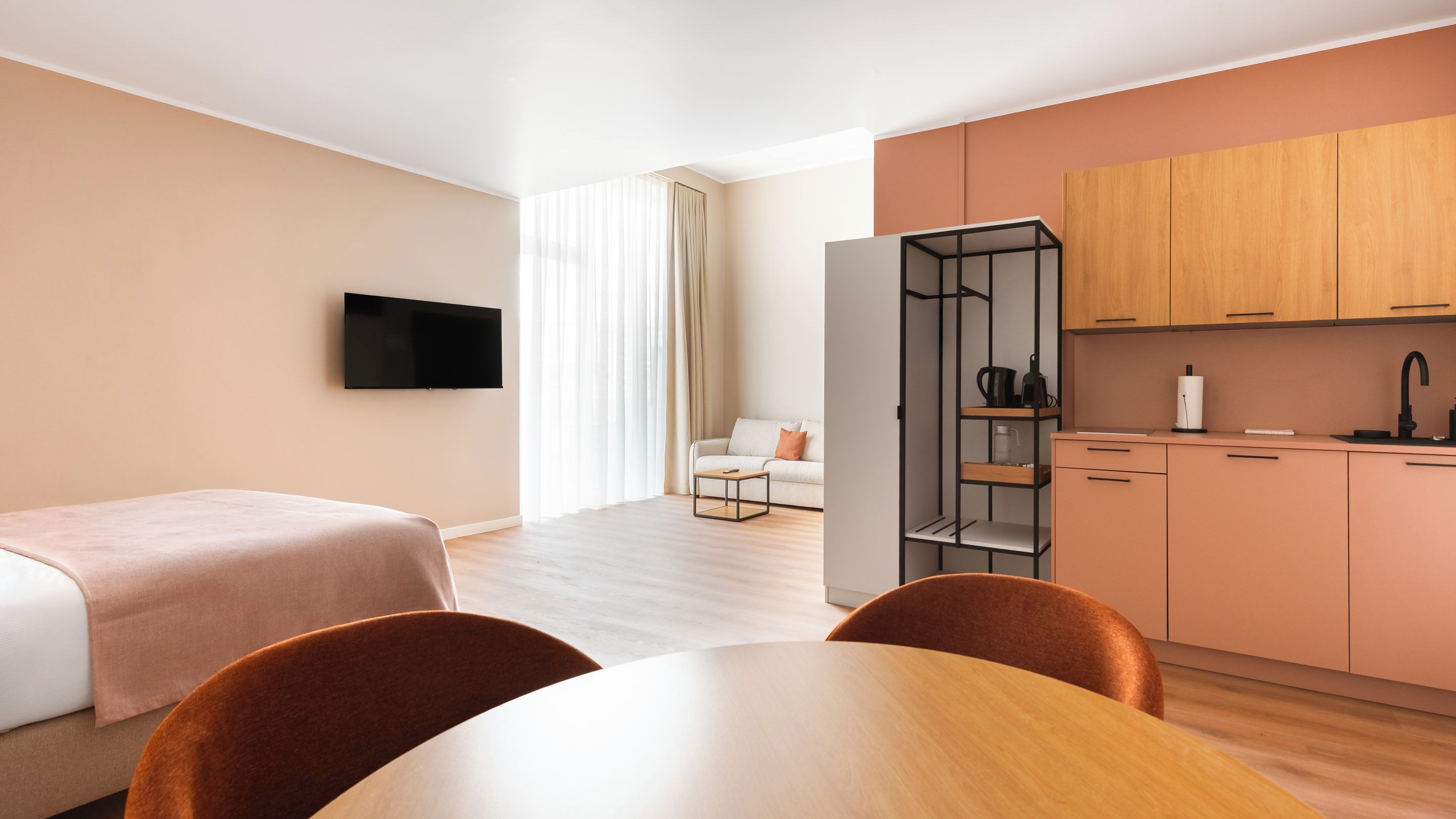 Ein Hotelzimmer mit Bett, Fernseher, Esstisch und Küchenzeile.