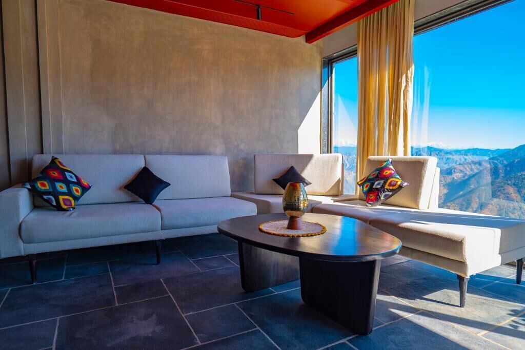 A modern living room with a sofa and armchairs, a coffee table, and a view of mountains.