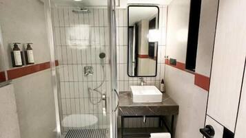 Un baño moderno con cabina de ducha de vidrio, lavabo y espejo.