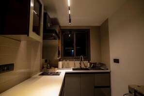 A compact kitchen with a built-in stove, a sink, and a window above the countertop.