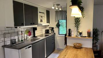 A modern kitchen with a wooden countertop, black cabinets, and a window with a view.
