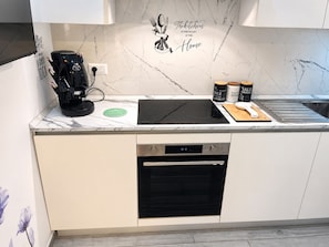 A modern kitchen with a built-in dishwasher, a coffee machine, and a marble backsplash. - Domus Acquedotti (Roma)