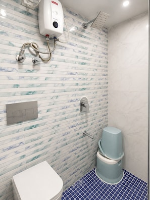 A bathroom with a marble-patterned wall, a showerhead, a toilet, and a bidet. - ZEST STAYS GOREGAON WEST (Mumbai)