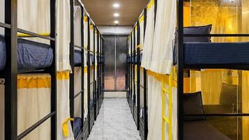 A corridor with bunk beds, wooden ceiling, and a marble floor.