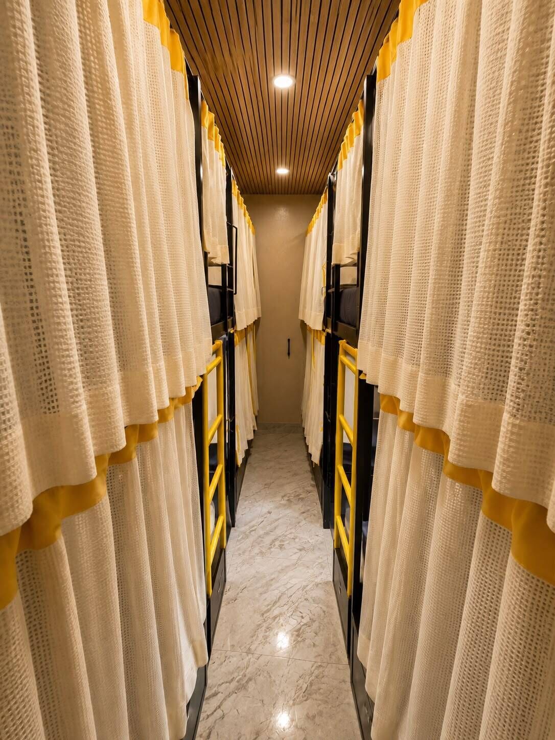 A corridor with bunk beds, wooden ceiling, and a marble floor.