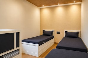A small, compact room with two single beds, a built-in TV, and a wooden ceiling. - ZEST STAYS GOREGAON WEST (Mumbai)