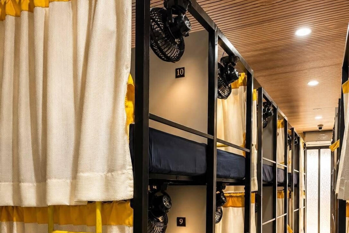 A corridor with bunk beds, each with a number sign, and a ladder in front of one bed.