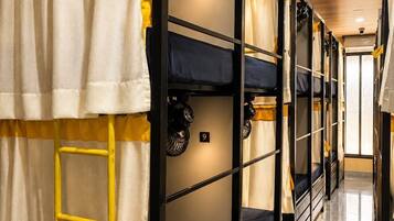 A corridor with bunk beds, each with a number sign, and a ladder in front of one bed.