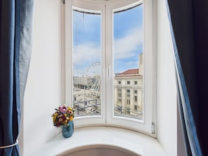 A bay window with a view of a Ferris wheel and buildings.