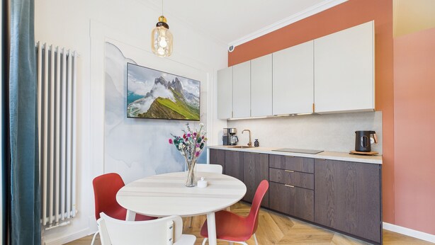 Une cuisine moderne avec un plan de travail blanc, des meubles de couleur foncée et une plaque de cuisson à une seule bouche.