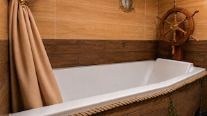 Una bañera con pared de madera y decoración de timón.