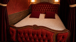 Una cama con cabecera capitonada, dos almohadas y estructura de madera.