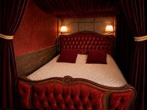Een bed met een gestoffeerd hoofdbord, twee kussens en een houten frame.