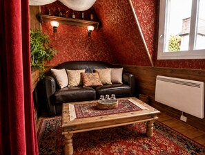Een gezellige kamer met een leren bank, een houten bijzettafeltje en een kamerbreed tapijt.
