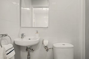 A bathroom with a white sink, mirror, and toilet. - El Rincón de la Mancebía Apartment (Alcalá de los Gazules)