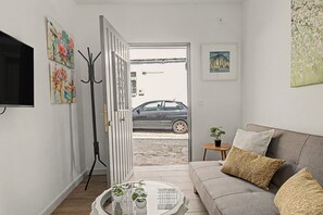 A living room with a sofa, a coffee table, and a door leading outside. - El Rincón de la Mancebía Apartment (Alcalá de los Gazules)