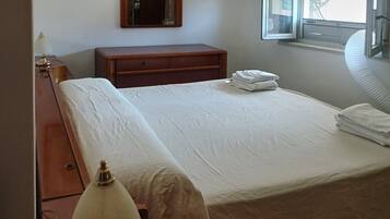 Une chambre d’hôtel avec un lit, une table de chevet, une lampe, une fenêtre donnant sur un paysage agréable et une porte.