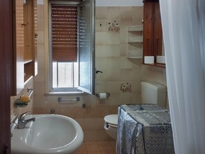 Ein Badezimmer mit Waschbecken, Toilette und einem Fenster mit Jalousien.