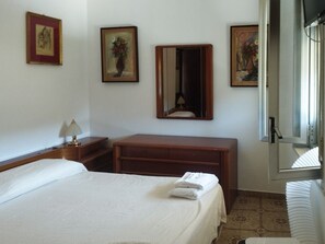 Ein Hotelzimmer mit einem Bett, einem Holzschrank, einem Spiegel und gerahmten Bildern an den Wänden.