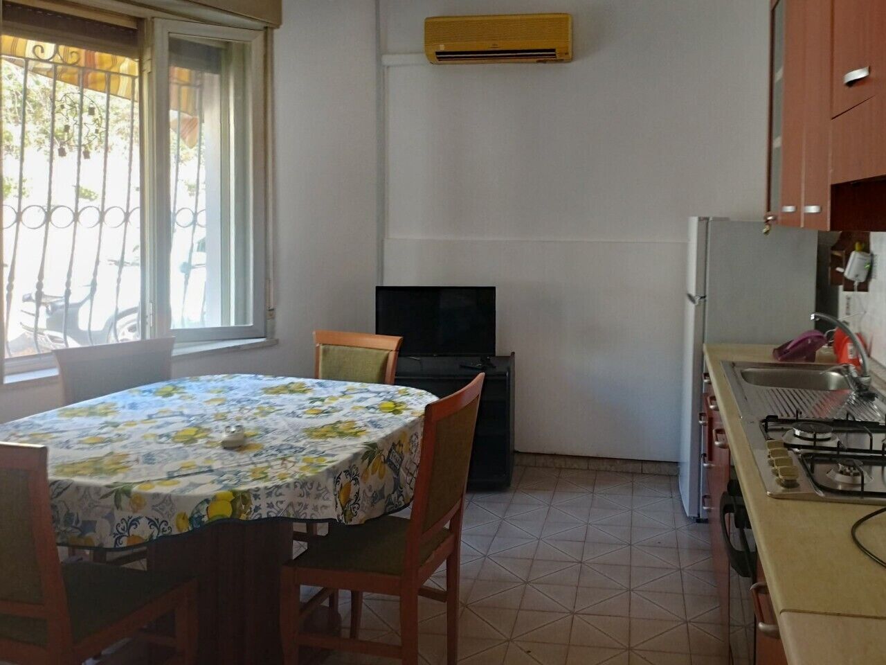 Une cuisine de taille réduite, équipée d’une cuisinière à gaz, d’un évier et d’une fenêtre donnant sur l’extérieur.