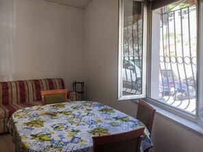 Ein Zimmer mit Esstisch, einer Couch und einem Fenster mit Blick auf parkende Autos.