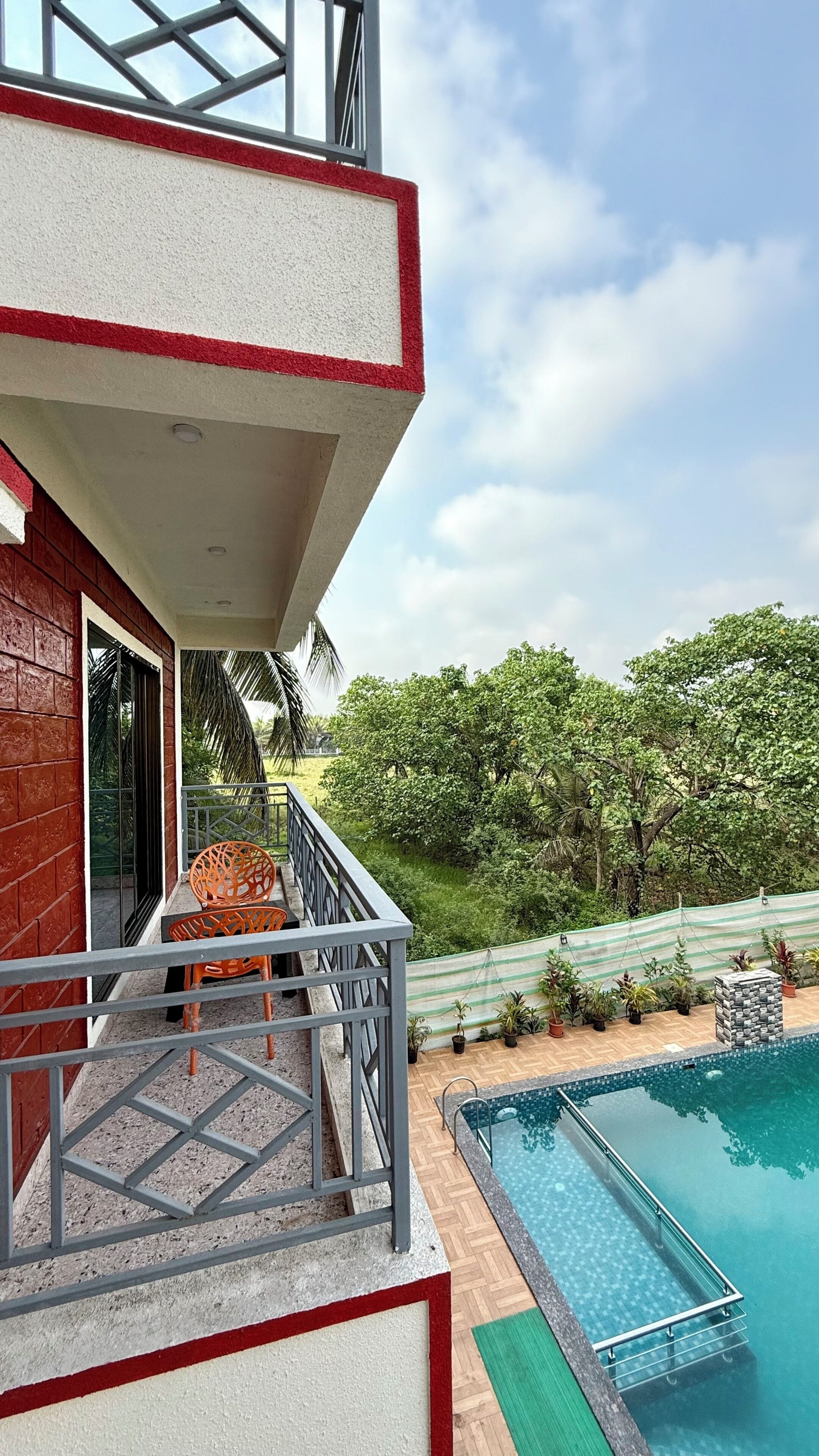 A residential balcony with a pool, surrounded by greenery.