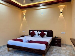 A hotel room with a bed, bedside tables, and a ceiling light fixture. - Coral Cove Resort (Alibag)