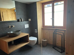 Kylpyhuoneessa on puinen allaskaappi, kivinen pesuallas, wc ja ikkuna, jossa on sälekaihtimet.