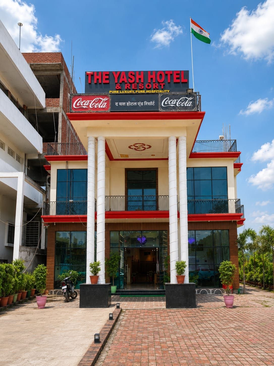 A hotel with a Coca-Cola sign, a flag, and a modern entrance.