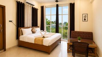 Una habitación de hotel con cama, sofá, una mesita y un balcón con cortinas.