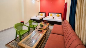 Habitación de hotel con dos camas, un sofá, una mesa de centro y una silla verde.