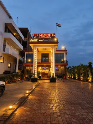 A hotel entrance with a Coca-Cola sign, a flag, and a Coca-Cola logo on the building. - The Yash Hotel And Resort (Faizabad)