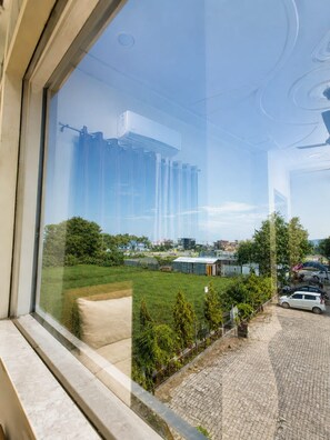 A view through a window with a clear sky, a grassy area, and a paved path. - The Yash Hotel And Resort (Faizabad)