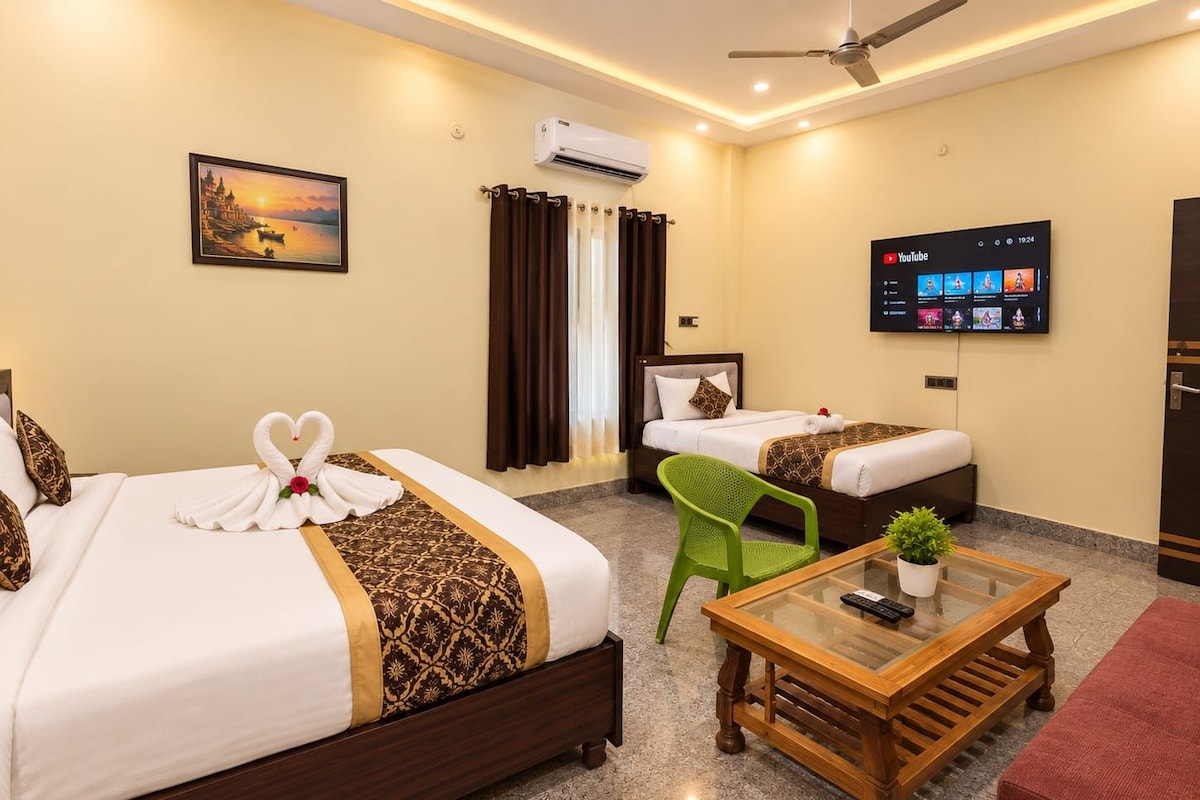 A hotel room with two beds, a TV, a ceiling fan, and a painting on the wall.