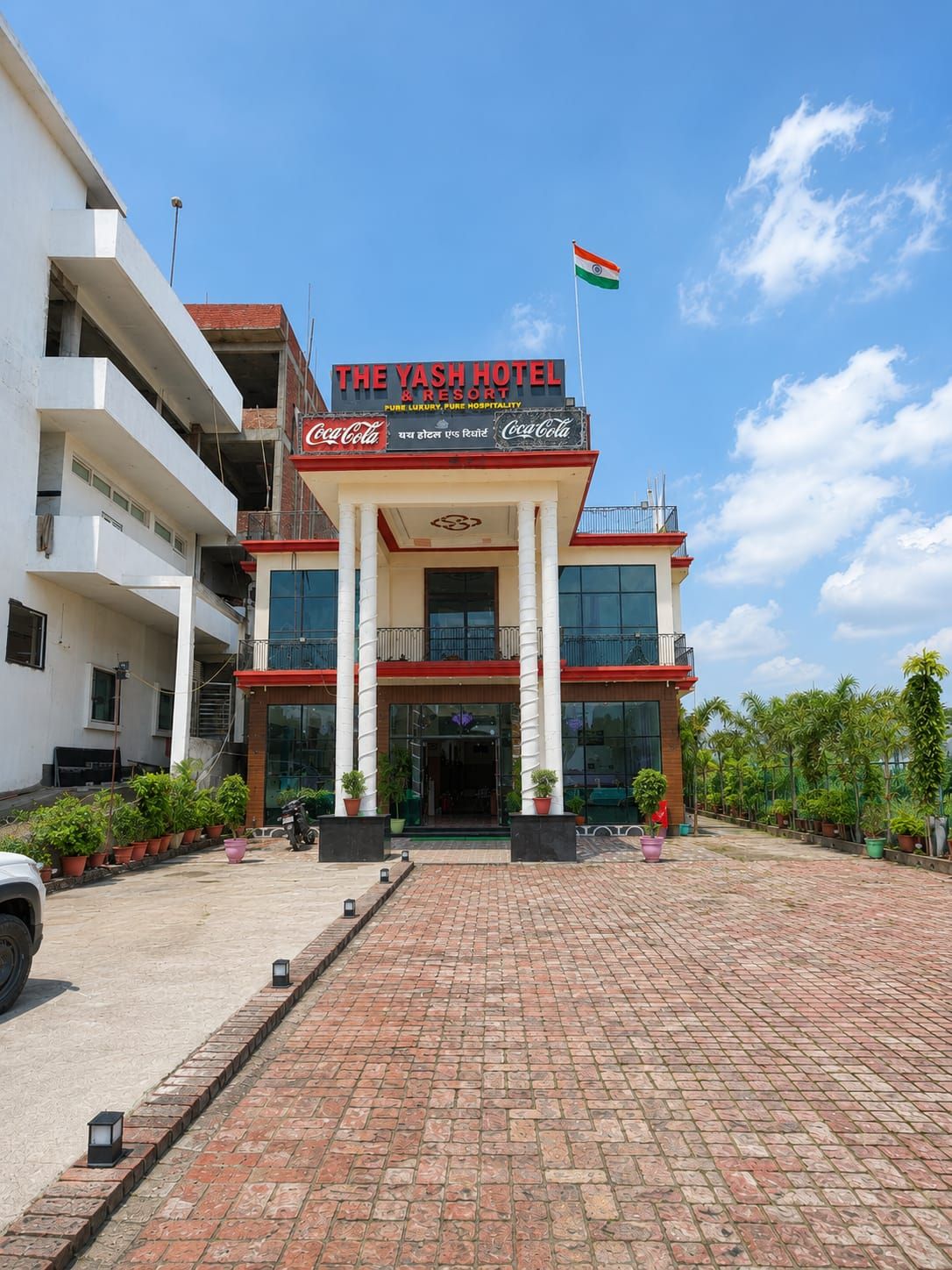 Un hotel con un letrero de Coca-Cola, una bandera y una entrada pavimentada.