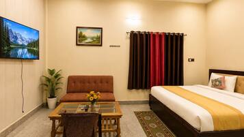 A hotel room with a bed, a sofa, a TV, a painting, and a window with curtains.