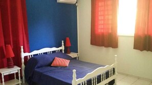 Une chambre à coucher avec un cadre de lit blanc, une couvre-lit bleue et des rideaux rouges.